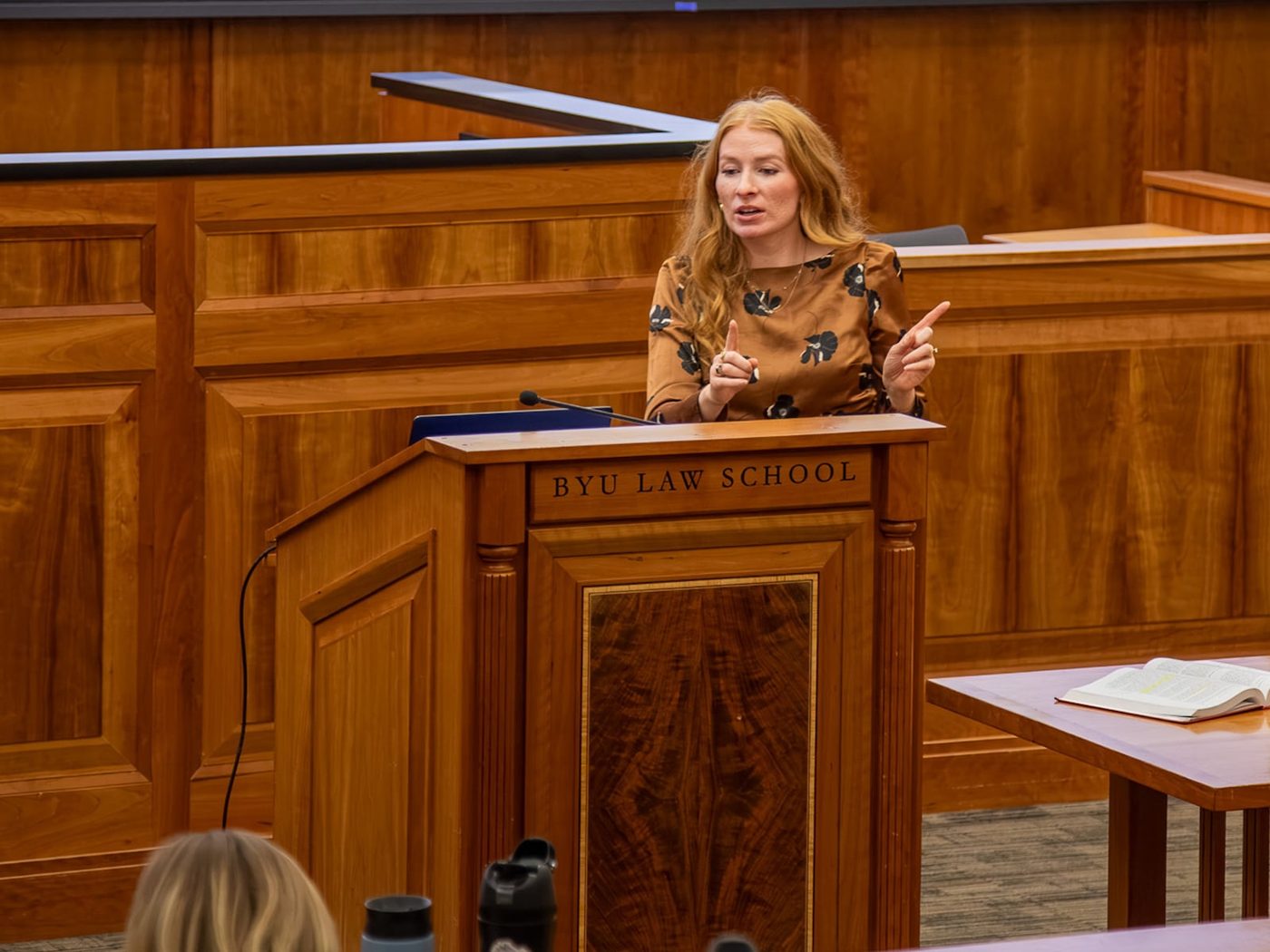 Professor Kelsey Baer Flores teaching from the lectern in a wood-paneled BYU Law School classroom