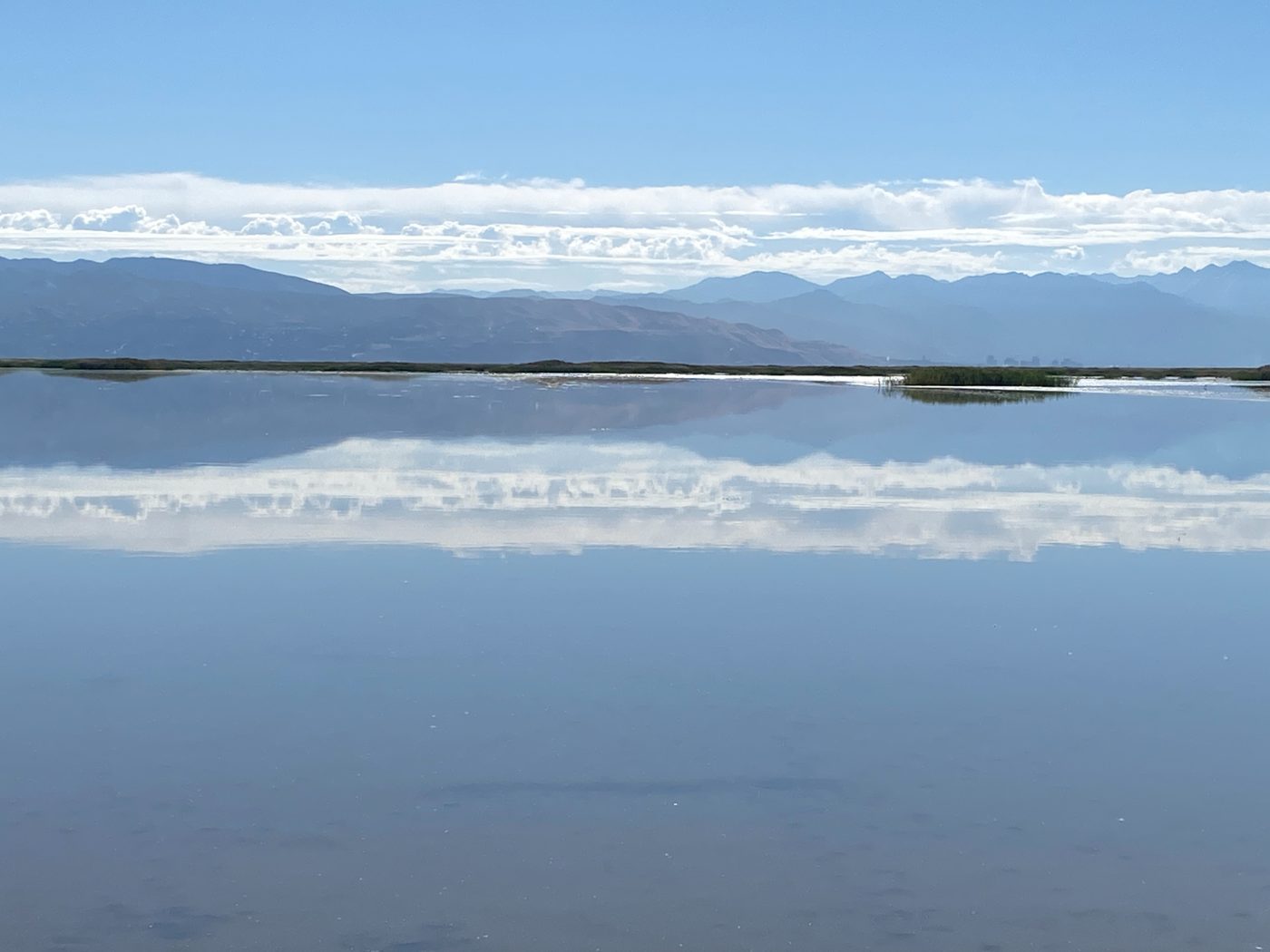 Calm water at Farmington Bay on the Great Salt Lake reflecting clouds and distant mountains