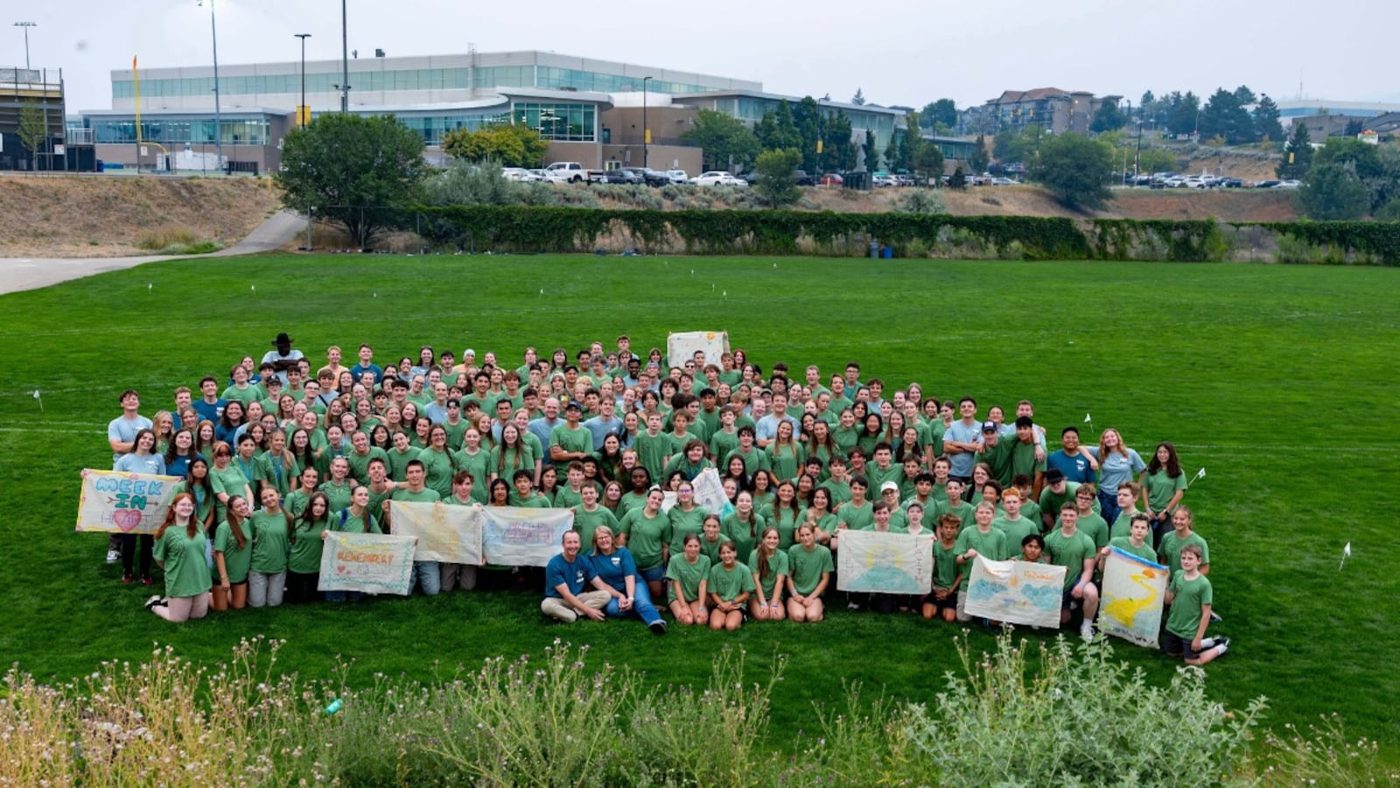 A large group of youth in matching green shirts posing on a lawn at an FSY conference in Kamloops, British Columbia