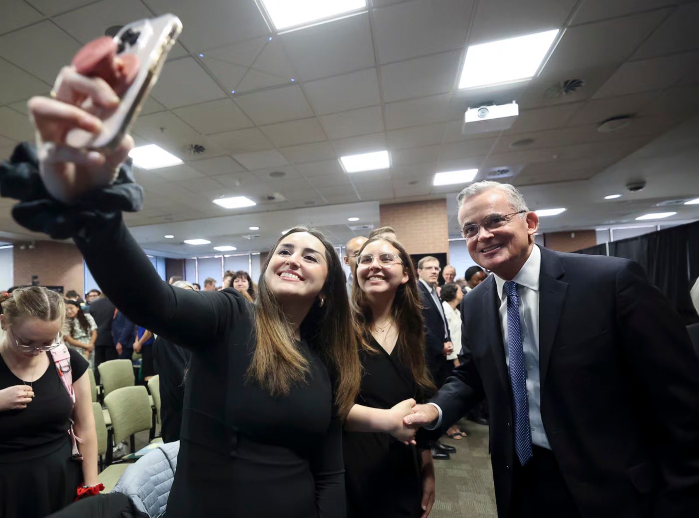 A student holding up a phone to take a selfie with Elder Patrick Kearon after the devotional