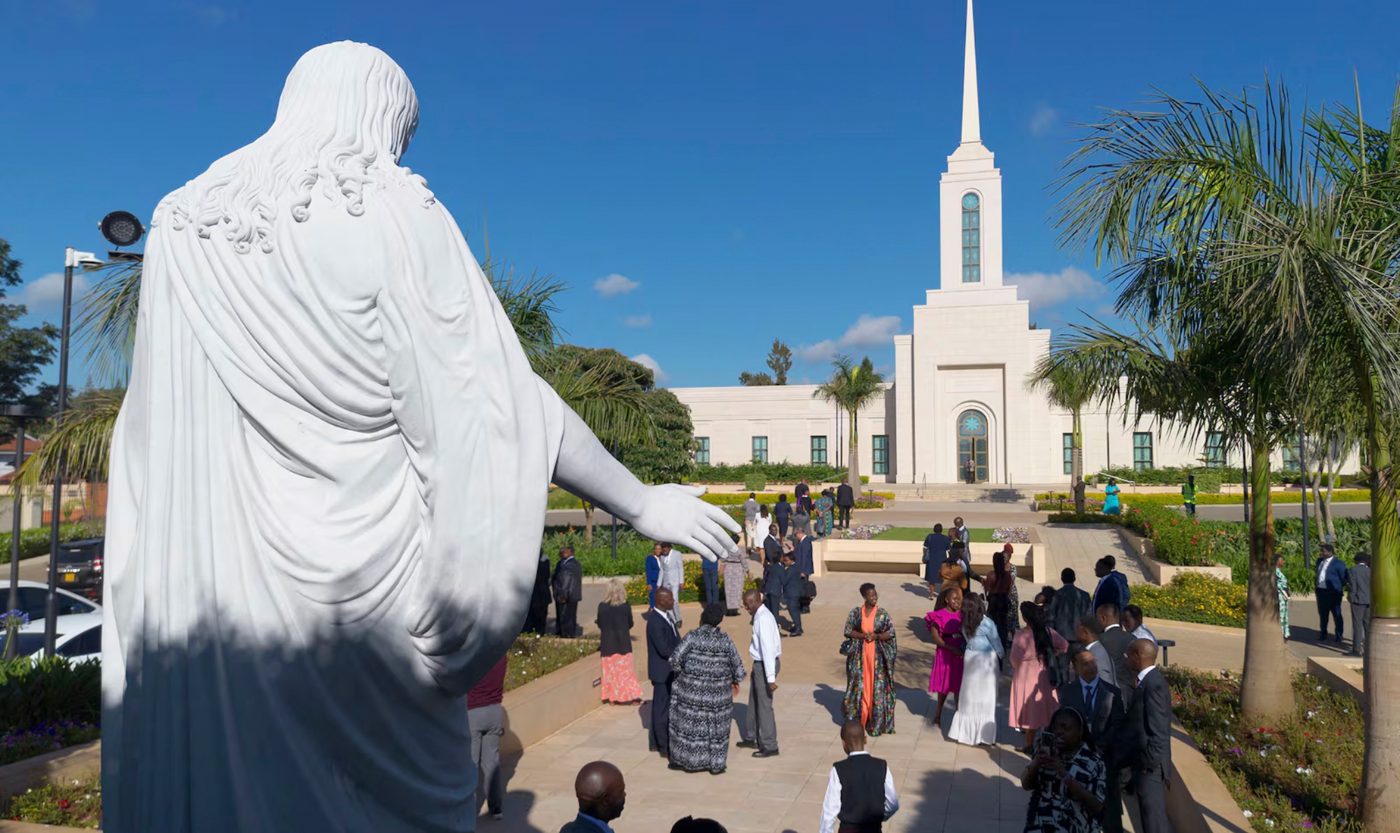 A Christus statue in the foreground with the white Nairobi Kenya Temple and arriving visitors beyond