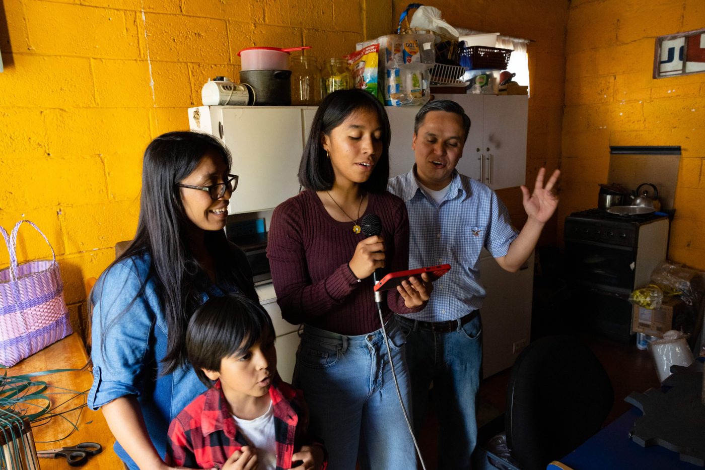 A family singing together at home while one daughter holds a phone showing the music