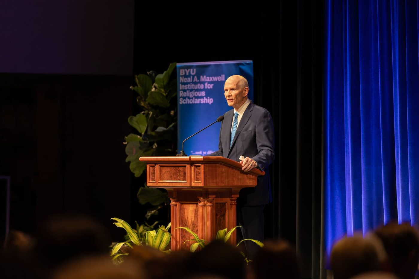 Elder Dale G. Renlund speaking at a pulpit at the Neal A. Maxwell Institute